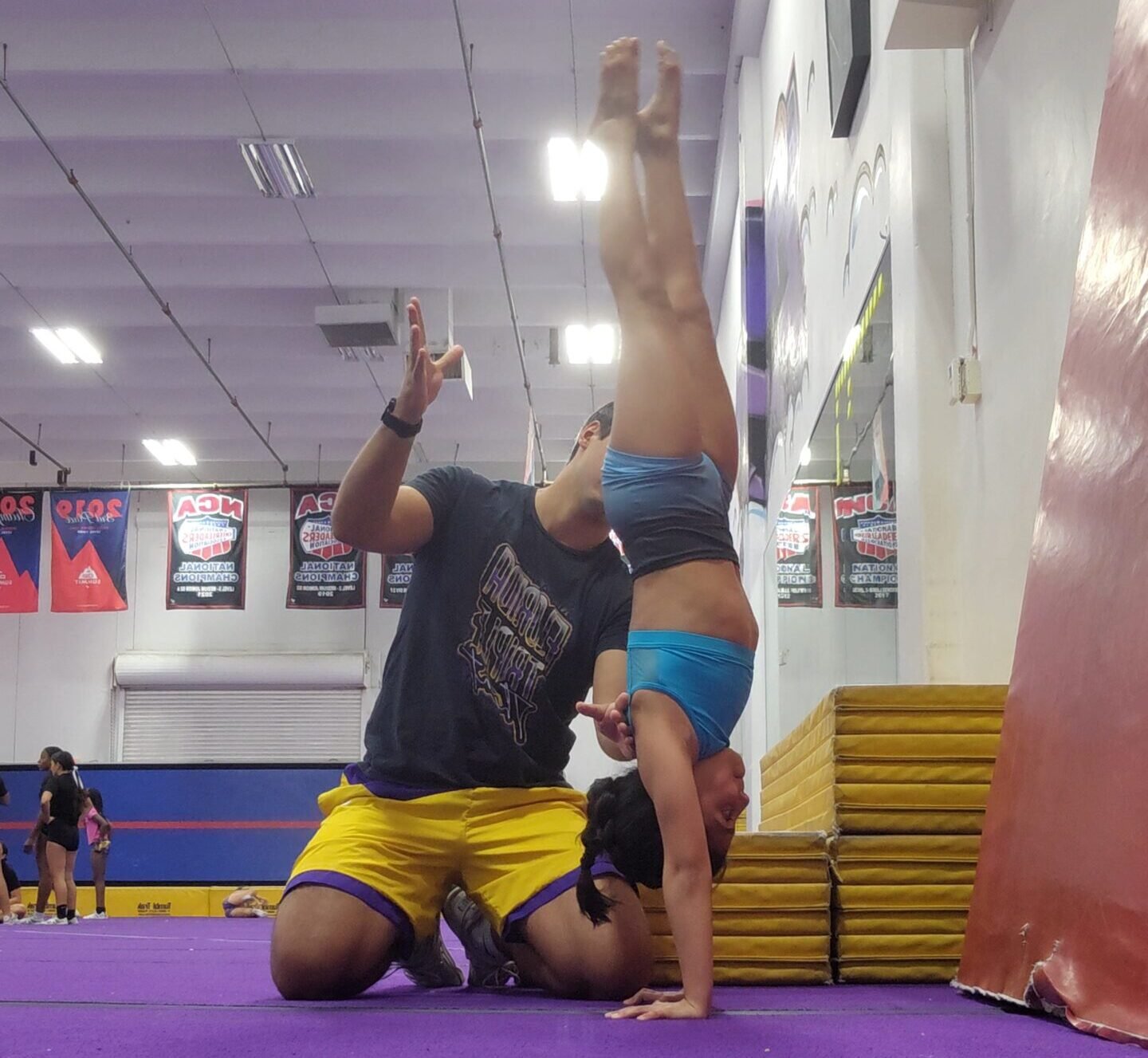Coach Diego Frez assisting an athlete during tumbling training